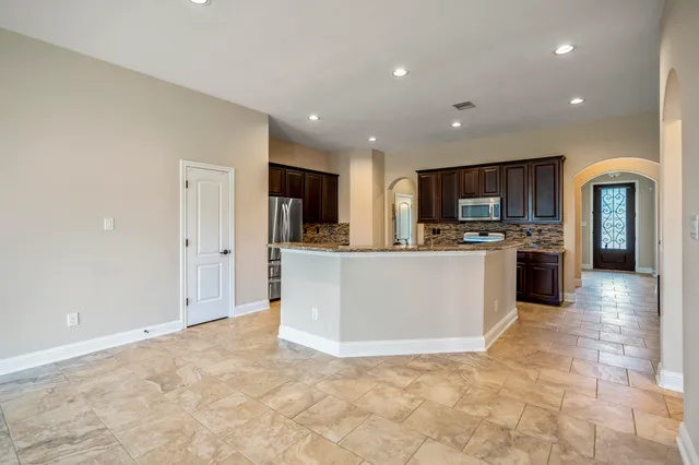 a view of kitchen with kitchen island stainless steel appliances a refrigerator a stove top oven a sink dishwasher and white cabinets