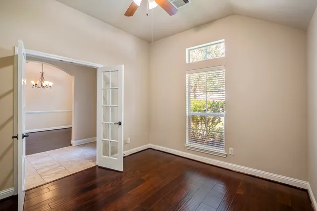 an empty room with wooden floor cabinet and windows