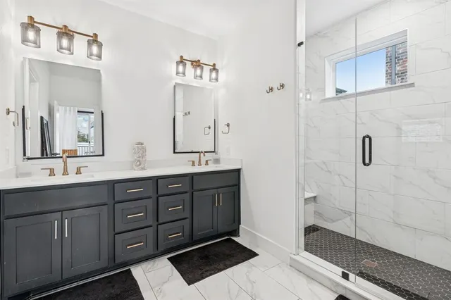 a spacious bathroom with double vanity sink a mirror and shower