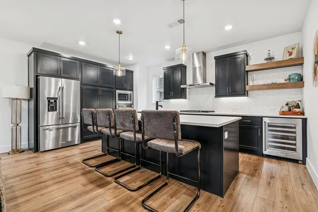 a kitchen with stainless steel appliances kitchen island granite countertop a refrigerator a stove and a wooden floors
