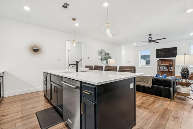 a kitchen with stainless steel appliances granite countertop a sink a stove and a wooden floor