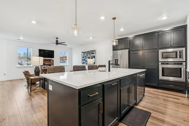 a kitchen with a sink stainless steel appliances and wooden floor