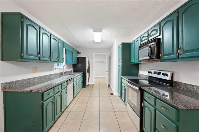a kitchen with stainless steel appliances granite countertop a stove a sink and a microwave