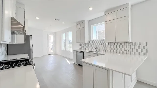 a kitchen with stainless steel appliances a sink a stove a refrigerator and cabinets