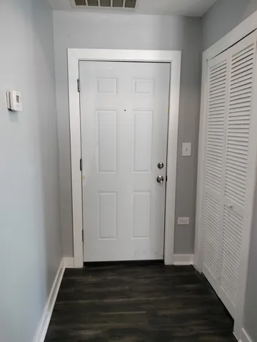 a view of an empty room with wooden floor and closet