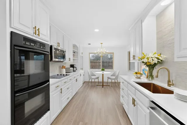 a kitchen with stainless steel appliances white cabinets a sink and a stove