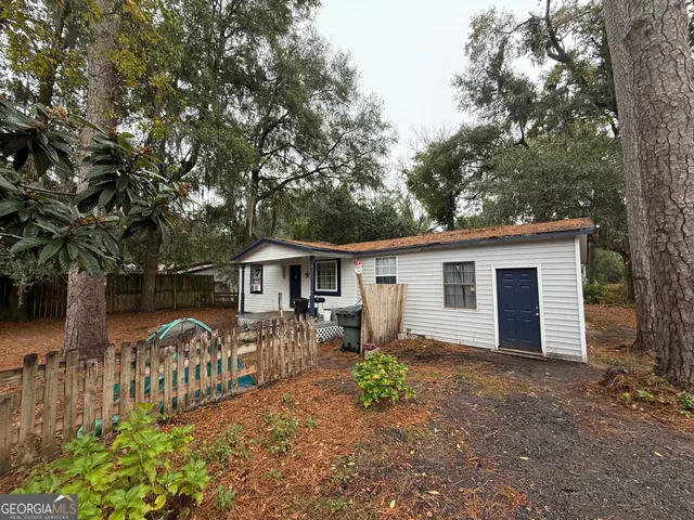 a view of a house with wooden fence and a large tree