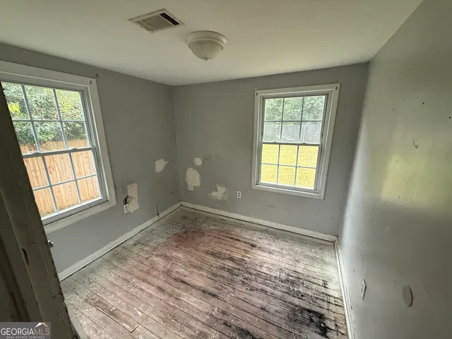 a view of an empty room with wooden floor and a window