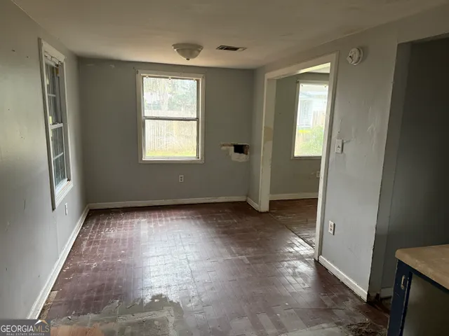 a view of an empty room with window and wooden floor
