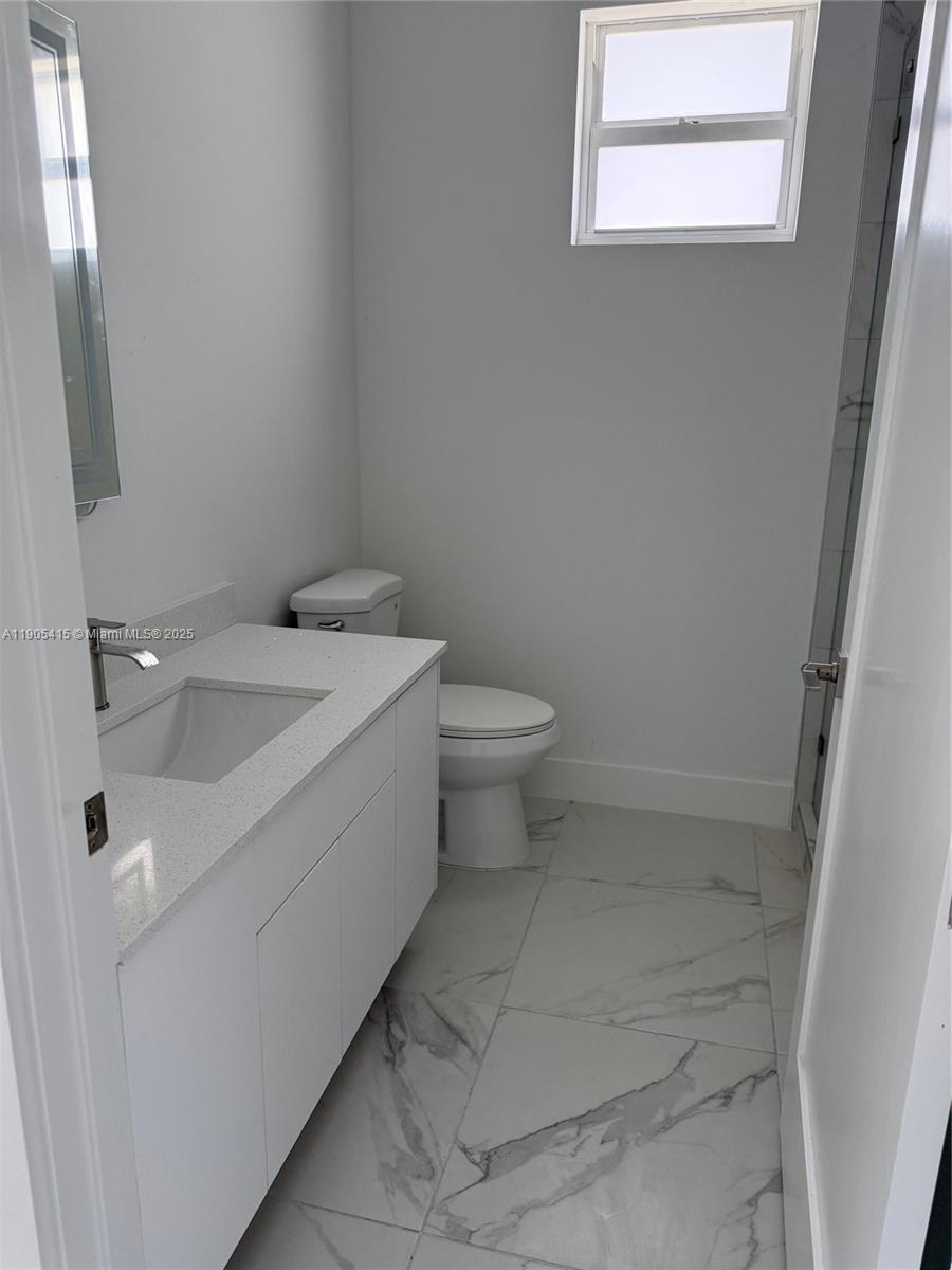 617 Valley Avenue Lehigh Acres, FL 33974 - Photo 27 of 46 a bathroom with a sink a toilet and a window