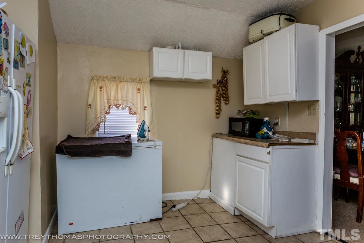 1126 Boyer Street Raleigh, NC 27610 - Photo 5 of 9 a white kitchen with stainless steel appliances a stove a refrigerator a sink and cabinets