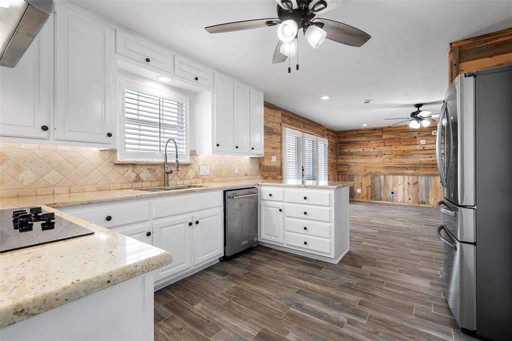 5112 Old Caufield Ranch Road McGregor, TX 76657 - Photo 14 of 38 Kitchen featuring stainless steel appliances, white cabinetry, light stone counters, wood walls, and recessed lighting