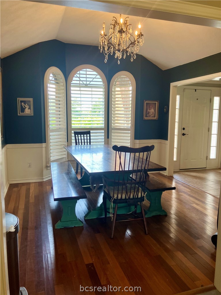 5660 Falling Water Bryan, TX 77808 - Photo 15 of 27 Dining area featuring dark hardwood / wood-style flooring, vaulted ceiling, and an inviting chandelier