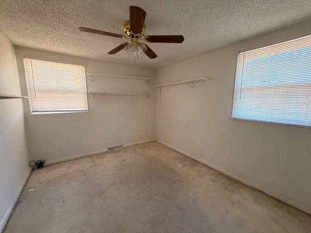 an empty room with windows and fan