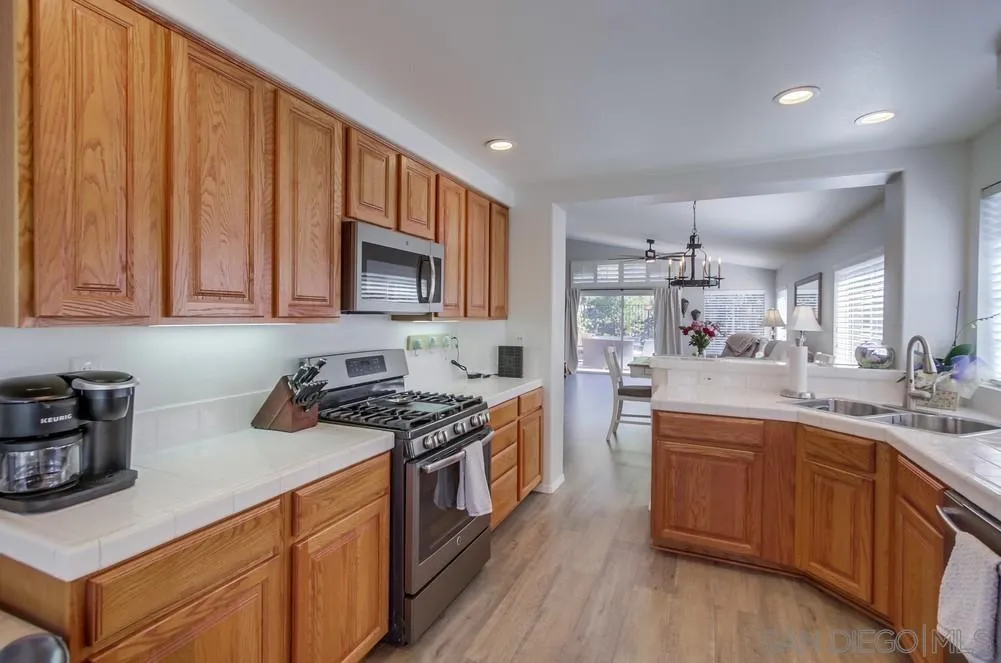 1966 Verbena Terrace Alpine, CA 91901 - Photo 16 of 41 a kitchen with kitchen island granite countertop wooden cabinets and white appliances