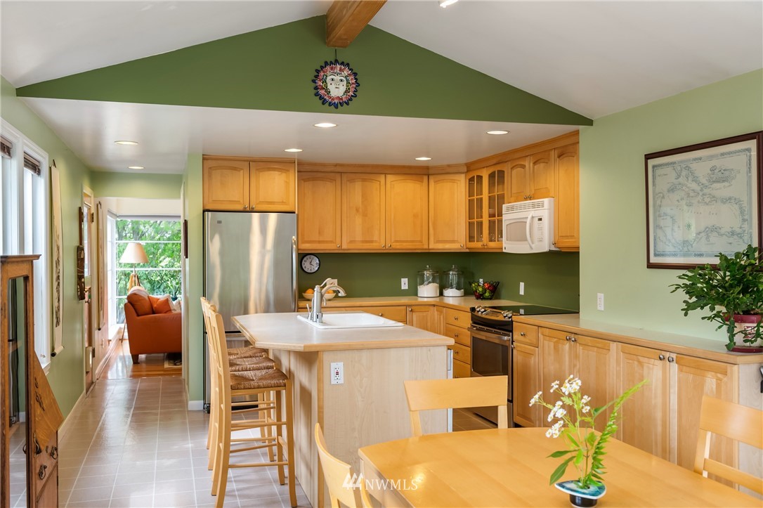 2315 North 57th Street Seattle, WA 98103 - Photo 12 of 35 a kitchen with stainless steel appliances kitchen island granite countertop a refrigerator a stove and a dining table with wooden floor