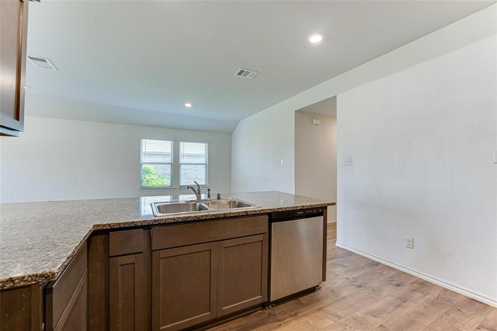 Kitchen island with granite countertops, integrated double basin sink, and stainless steel dishwasher