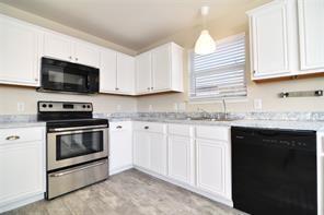 321 South Chestnut Street Forney, TX 75126 - Photo 9 of 27 a kitchen with granite countertop a sink dishwasher a stove and a microwave oven with cabinets
