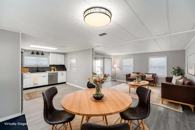a kitchen with stainless steel appliances granite countertop a dining table chairs stove refrigerator and cabinets