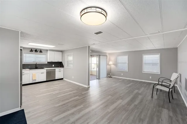 a view of kitchen and empty room with wooden floor