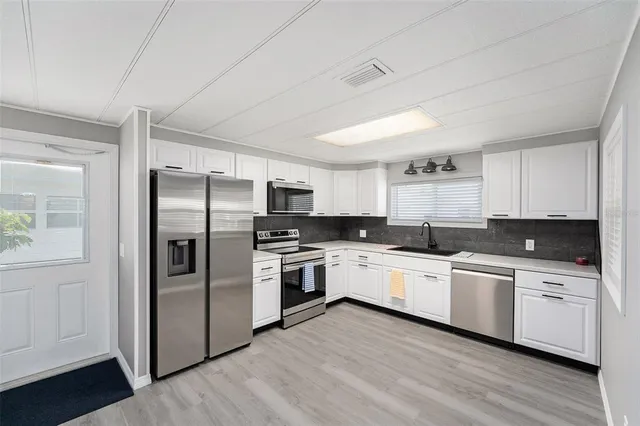 a kitchen with stainless steel appliances a refrigerator sink and microwave