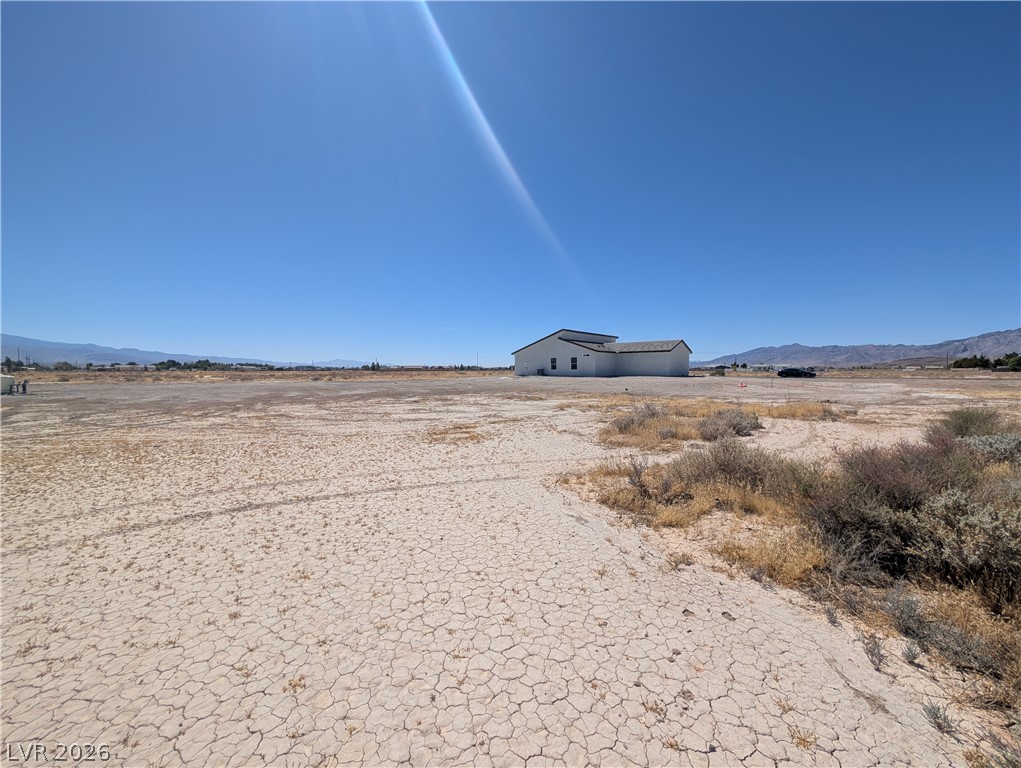 4670 Medicine Man Road Pahrump, NV 89048 - Photo 29 of 36 A spacious, undeveloped lot with a distant structure, ready for visionary development.