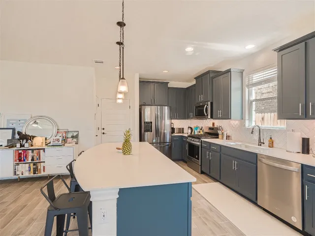 a kitchen with kitchen island a stove a sink a refrigerator and chairs