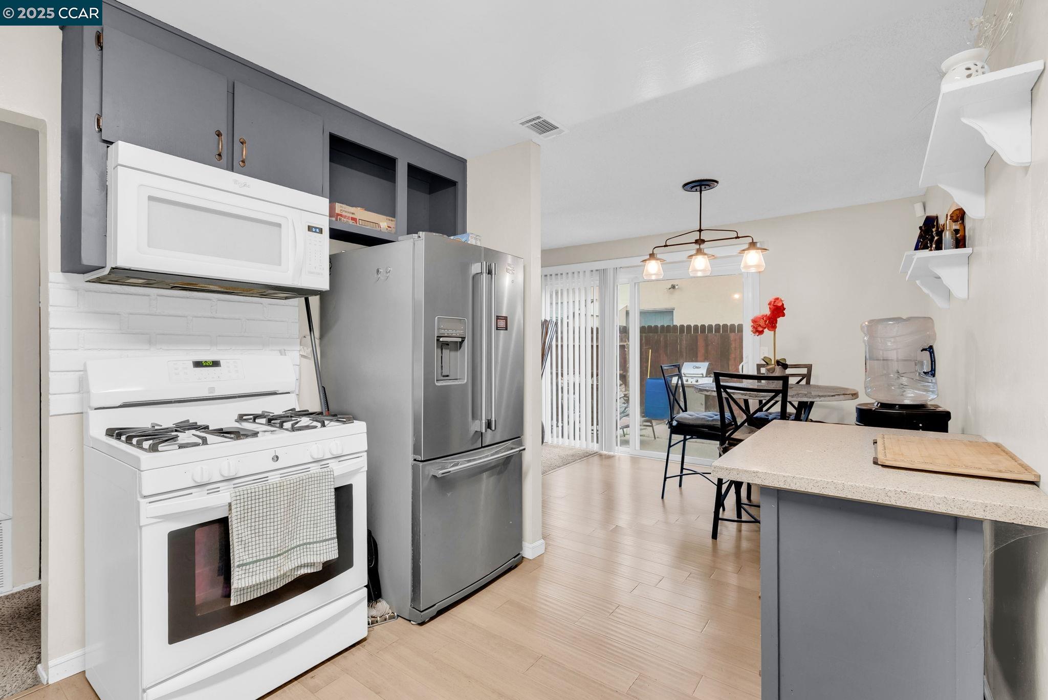 265 Tahoe Drive Rio Vista, CA 94571 - Photo 9 of 24 a kitchen with stainless steel appliances a stove a refrigerator and a dining table with wooden floor