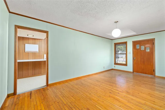 a view of an empty room with window and wooden floor
