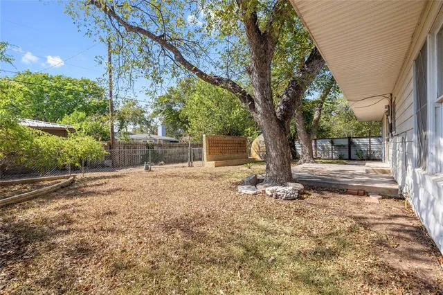 a backyard of a house with a large tree and wooden fence