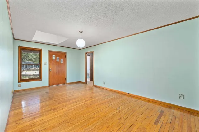 a view of an empty room with window and wooden floor