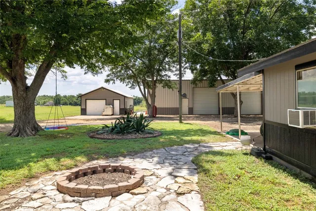 a backyard of a house with plants and large tree