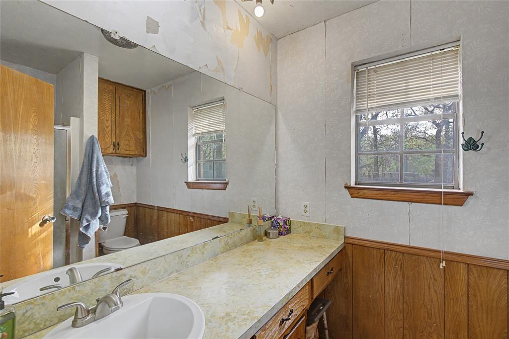 243 County Road 3851 Poolville, TX 76487 - Photo 18 of 34 a bathroom with a granite countertop sink and a mirror