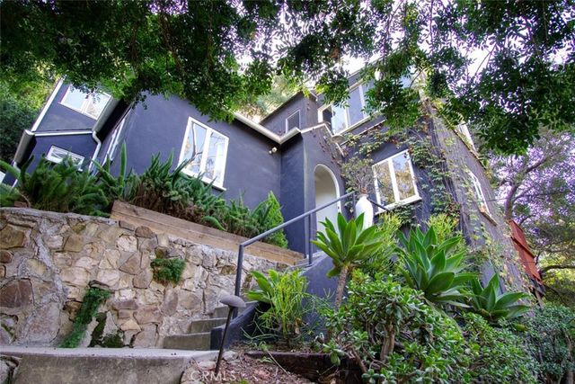 a front view of a house with plants and garden