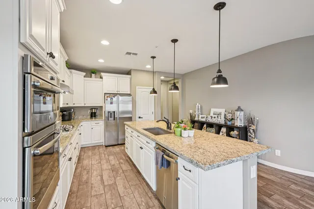 a large kitchen with stainless steel appliances kitchen island granite countertop a lot of counter space and a wooden floor