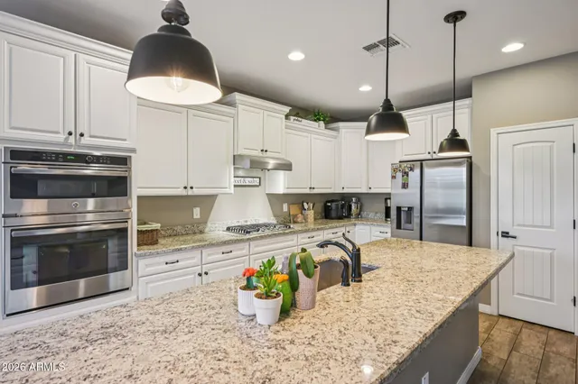 a kitchen with stainless steel appliances granite countertop a sink a stove and a wooden floors