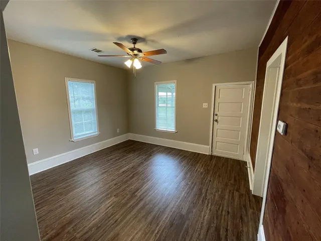 a view of empty room with wooden floor and fan