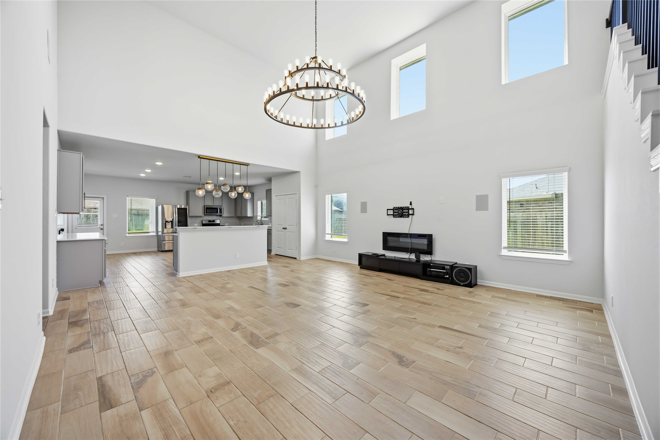 2402 Mount Dana Drive Rosharon, TX 77583 - Photo 5 of 28 Expansive open-concept living area with high ceilings, modern show-stopping chandelier, and abundant natural light, seamlessly connecting to a sleek kitchen with stainless steel appliances.