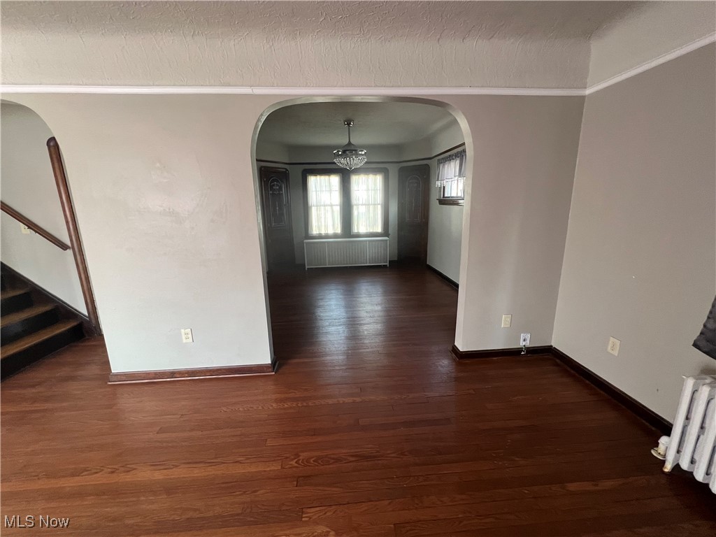 3505 Silsby Road Cleveland, OH 44118 - Photo 24 of 34 Unfurnished living area with arched walkways, wood finished floors, radiator heating unit, and radiator