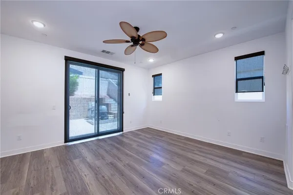 a view of an empty room with a window and wooden floor