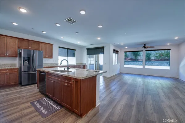 a large kitchen with stainless steel appliances granite countertop a large counter top a sink and a refrigerator