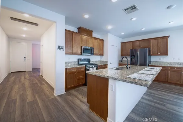 a kitchen with stainless steel appliances granite countertop wooden cabinets a sink dishwasher a stove and a refrigerator