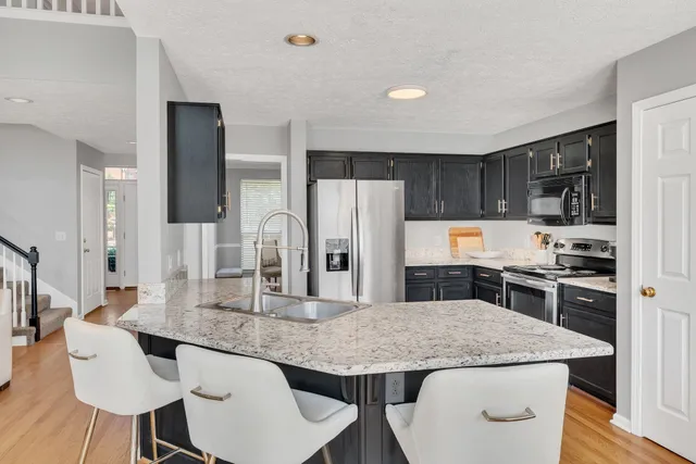 a kitchen with stainless steel appliances granite countertop a kitchen island a stove a table and chairs