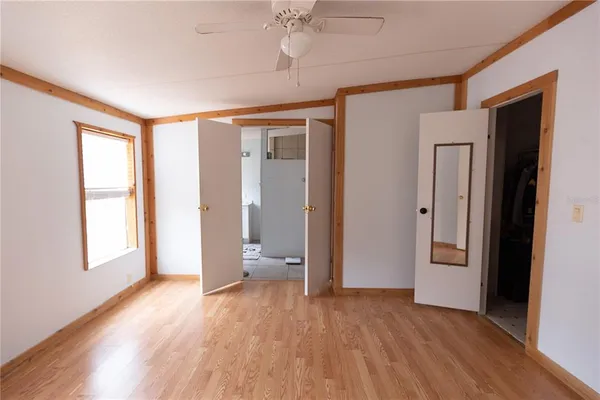 a view of an empty room with a window and wooden floor