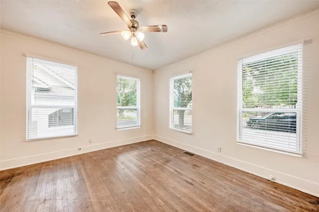 a view of an empty room with a window and wooden floor