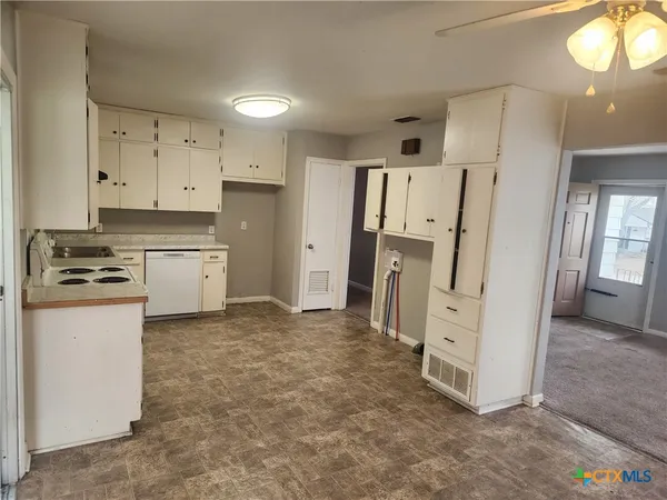 a kitchen with white cabinets and refrigerator