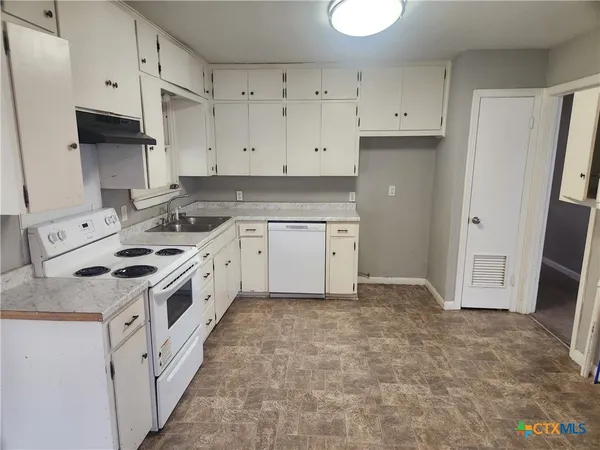 a kitchen with white cabinets and white appliances