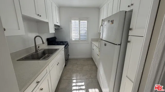 a kitchen with a refrigerator sink and cabinets