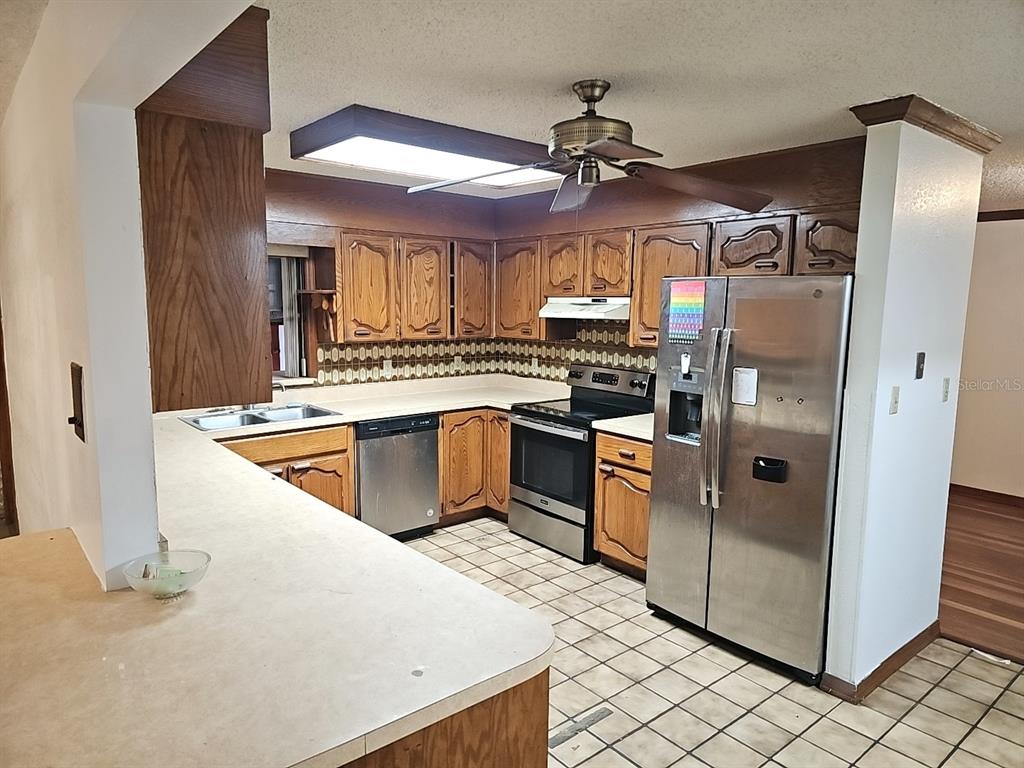 71 Dobson Street Orlando, FL 32805 - Photo 4 of 27 a kitchen with stainless steel appliances granite countertop a sink a stove a refrigerator a washer dryer and white cabinets