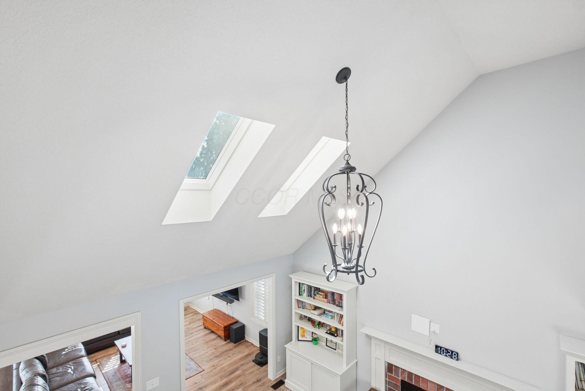 9435 Concord Road Powell, OH 43065 - Photo 28 of 77 Vaulted ceiling with two skylights and an ornamental chandelier
